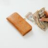 Photo by Karolina Grabowska: https://www.pexels.com/photo/person-holding-money-on-white-table-beside-a-wallet-7680469/