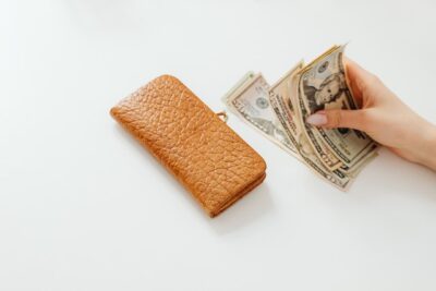 Photo by Karolina Grabowska: https://www.pexels.com/photo/person-holding-money-on-white-table-beside-a-wallet-7680469/