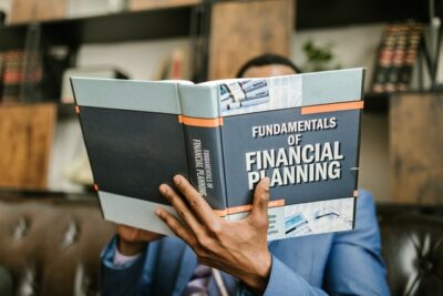 Photo by RODNAE Productions: https://www.pexels.com/photo/person-reading-a-book-about-fundamentals-of-financial-planning-7821487/