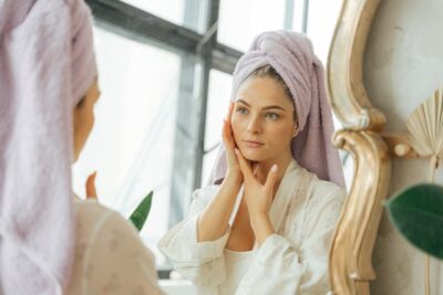 Photo by ANTONI SHKRABA: https://www.pexels.com/photo/woman-in-white-bathrobe-with-head-towel-looking-at-a-mirror-touching-her-face-5205667/