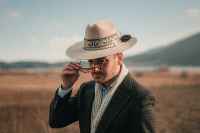 Photo by Safa Bakırcı: https://www.pexels.com/photo/man-in-cowboy-hat-putting-on-eyeglasses-in-field-7783510/