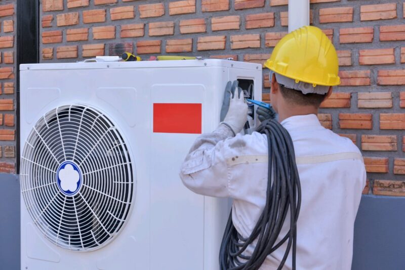 ShutterStock royalty-free image #1734979868, 'A young Asian air conditioner technician or air-conditioning installation technician is about to repair air conditioning in homes and buildings.Air conditioner repairmen work on home unit. ' uploaded by user #233987357, retrieved from ShutterStock on April 29th, 2022. License details available at https://www.shutterstock.com/license, image licensed under the ShutterStock Standard Image License
