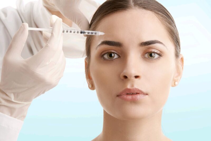 Adobe Stock royalty-free image #192860896, 'Woman at plastic surgery. Portrait of an attractive young woman receiving botox treatment. Isolated on light blue background.' uploaded by sepy, standard license purchased from https://stock.adobe.com/images/download/192860896; file retrieved on May 10th, 2019. License details available at https://stock.adobe.com/license-terms - image is licensed under the Adobe Stock Standard License
