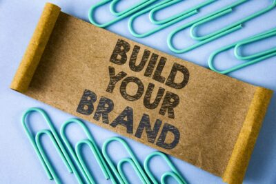 Adobe Stock royalty-free image #202252514, 'Text sign showing Build Your Brand. Conceptual photo create your own logo slogan Model Advertising E Marketing written on Folded Cardboard paper piece on plain blue background within Paper Pins.' uploaded by Artur, standard license purchased from https://stock.adobe.com/images/download/202252514; file retrieved on June 26th, 2019. License details available at https://stock.adobe.com/license-terms - image is licensed under the Adobe Stock Standard License