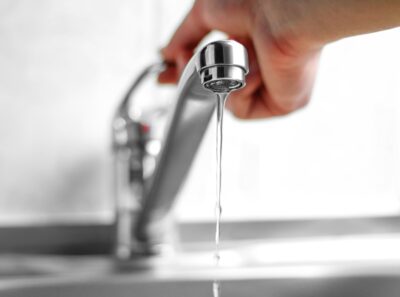 Adobe Stock royalty-free image #255702011, 'Hand opens the water tap. Close up' uploaded by OBprod, standard license purchased from https://stock.adobe.com/images/download/255702011; file retrieved on September 1st, 2019. License details available at https://stock.adobe.com/license-terms - image is licensed under the Adobe Stock Standard License