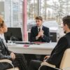 Photo by ANTONI SHKRABA: https://www.pexels.com/photo/man-in-a-suit-talking-with-a-couple-in-an-office-7144262/