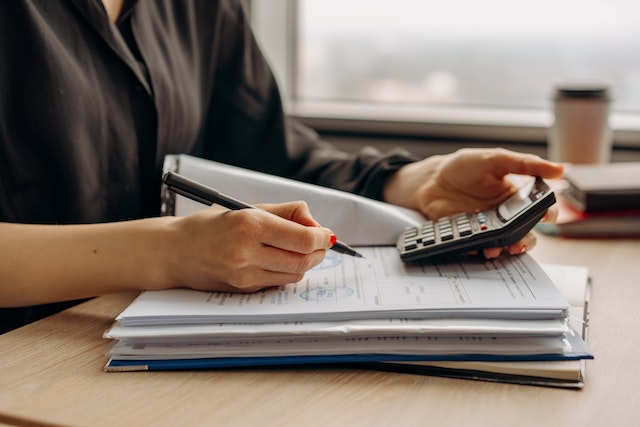 Photo by Mikhail Nilov: https://www.pexels.com/photo/person-in-long-sleeve-shirt-holding-a-calculator-8297031/
