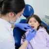 Photo by Nadezhda Moryak: https://www.pexels.com/photo/woman-in-white-button-up-shirt-wearing-face-mask-cleaning-the-girl-s-teeth-7800568/