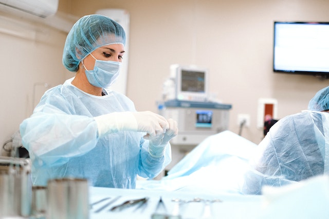 Photo by Anna Shvets: https://www.pexels.com/photo/woman-in-blue-dress-shirt-wearing-blue-mask-and-white-latex-gloves-4586984/